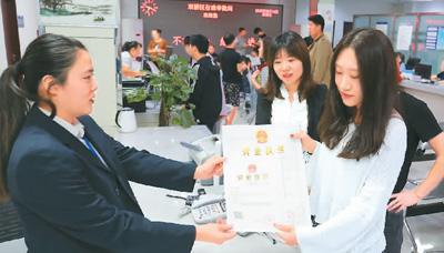 河北省承德市網(wǎng)絡(luò)代購(gòu)經(jīng)營(yíng)者陳晨(右)從工作人員手中接過(guò)帶有統(tǒng)一社會(huì)信用代碼的營(yíng)業(yè)執(zhí)照。 劉環(huán)宇攝(人民圖片)